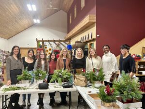 Membres de l'équipe CBTm derrière des pots de Noël avec fougères et baies